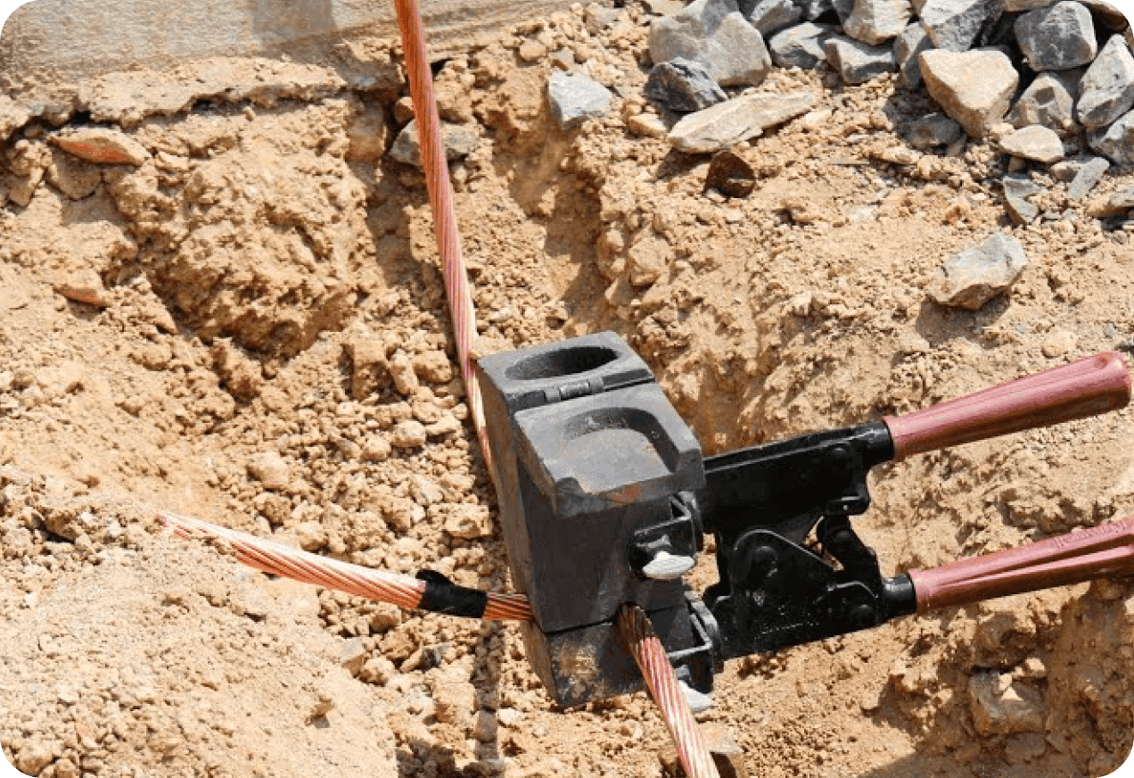 Electrical wires being connected using a crimping tool in a trench.